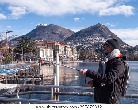 Lugano, Switzerland - january 30, 2015: Asian tourist while shooting a Selfie, in the background the city and Mount Bre snowy