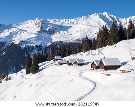 Foisch, Switzerland - February 7, 2015: Snowy mountain chalet in wood and illuminated by the sun create a aplendido winter scenery and characteristic of the Swiss Alps.