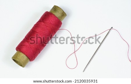 The sewing needle is a pointed tool and a red thread threaded into the eye of the needle. Designed for stitching clothing parts. Photo stock © 