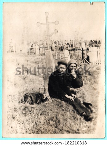 USSR  - CIRCA 1930s: Grand mother with her grand son sitting on grave