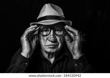 Artistic portrait of an old man with glasses and hat