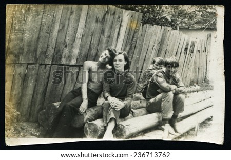Ussr - CIRCA 1980s: An antique Black & White photo show young people sitting on the logs near the fence