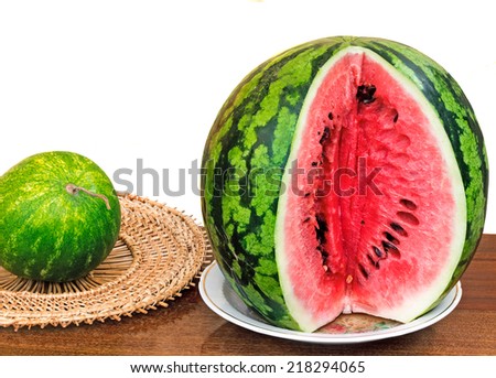 On a table surface on a dish the cut water-melon is located. It is presented on a white background.