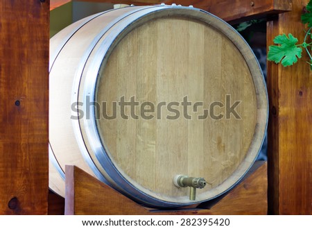 Large durable , made of natural oak, barrel for wine with a metal crane, is located on a convenient wooden stand.
