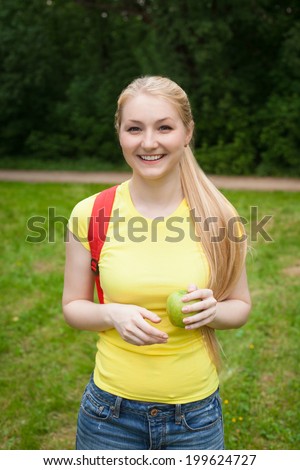 blonde girl with red rucksack and yellow t-shirt in the park at summer