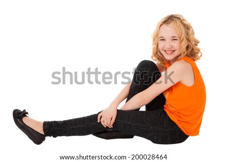 little smiling girl in orange clothes and black shoes sitting over white background