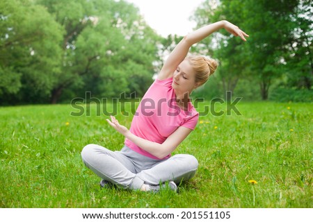 blonde girl outdoor in the park wearing grey shoes and pick t-shirt. yoga