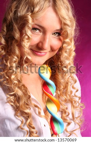 blonde curly smiling  girl holding lollipop on the pink background