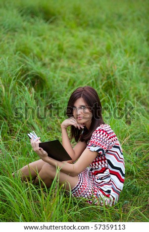 beautiful brunette girl in the park reading book in dress
