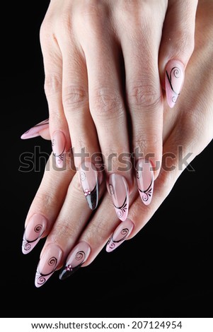 Pink painted nails and hands isolated on black background