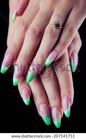 Green painted nails and hands isolated on black background