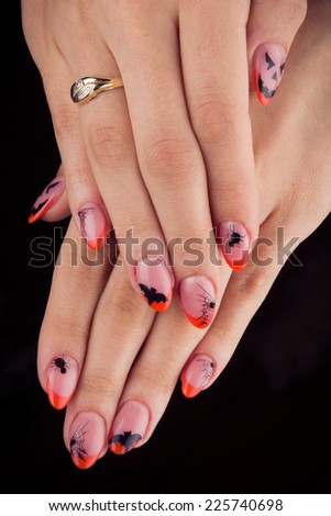 Pretty woman hand with perfect painted nails isolated on black background. Halloween, bat, spider, pumpkin