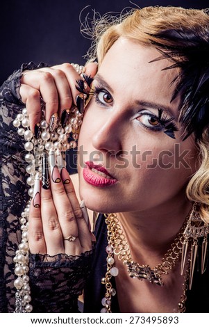 Retro portrait of beautiful blonde woman with gold and pearl jewels and extreme long nails. Gatsby, Vintage style. Isolated on black background