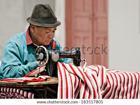 SAQUISILI, ECUADOR - AUGUST 18: A street tailor is making a traditional striped poncho with his old Singer sewing machine on August 18, 2012 in Saquisili, Ecuador