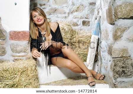 solar and attractive young woman in black dress sitting on stairs with ancient wall