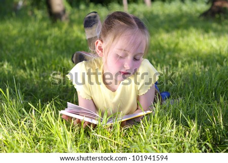 Portrait of little girl reading a book in the garden