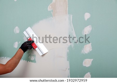 Hand with a spatula. Worker trowels putty on drywall with finishing putty Сток-фото © 