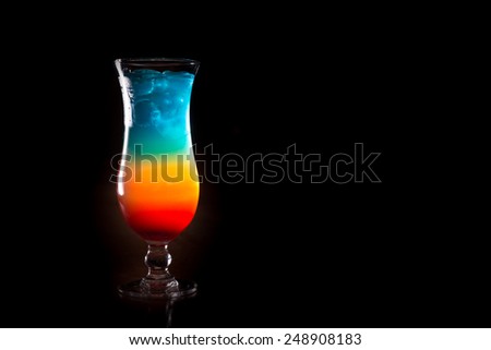 Rainbow cocktail on the bar stand with dark background. Shallow DOF