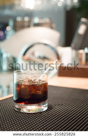Black russian cocktail on the bar stand on rubber mat. Shallow DOF