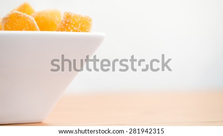 Crystallized ginger root  in white porcelain bowl. Bowl is cut vertically. Shallow DOF. Close-up photo, wide screen