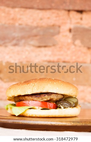 Classic homemade hamburger with onion rings and french fries on a wooden plate. Juicy homemade food. Vertical, macro