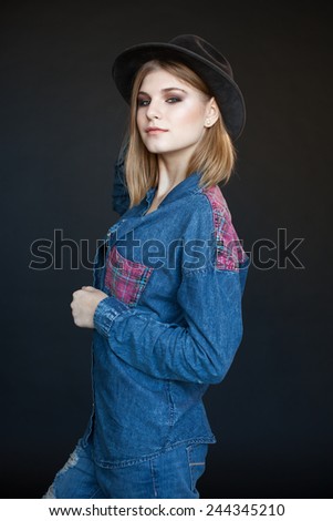 beautiful young model in a denim shirt and hat on a dark background