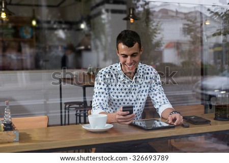 Fashionable and stylish young man relaxing with coffee, music and internet browsing at the cafe bar. Selective focus. Toned image.