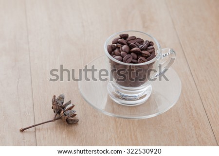 clear cup of coffee beans on wood vinyl background