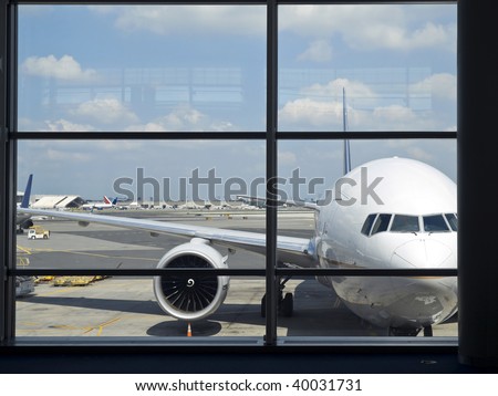 Parked aircraft on an airport through the gate window.