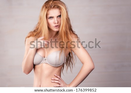 the red-haired girl posing on a light background, pointing to you