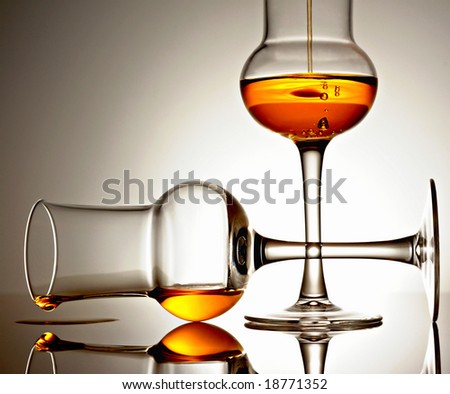 Two glasses with golden colored liquid on a reflective surface