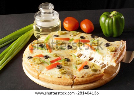 Vegetarian pizza slice being lifted with ingredients in the background