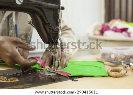 Bangalore, Karnataka, India - March 20, 2014: An unidentified traditional tailor stitches embroidered cloth using a sewing machine.
