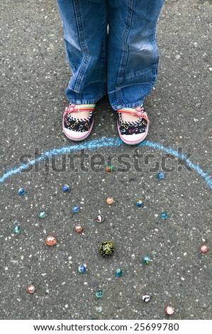 Young girl playing marbles within a chalk ring