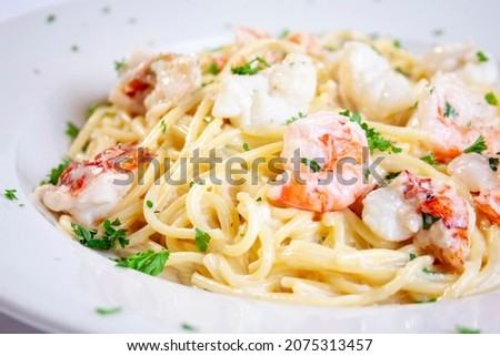 white porcelain plate tuscan seafood dish shrimp lobster spaghetti pasta noodles creamy Alfredo sauce garnish green parsley isolated Сток-фото © 