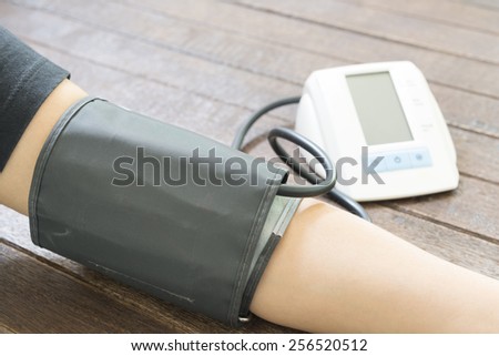 Woman checking blood pressure and heart rate with a digital blood pressure monitor.