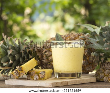 Pineapple juice and pineapple slice placed on a wooden table.