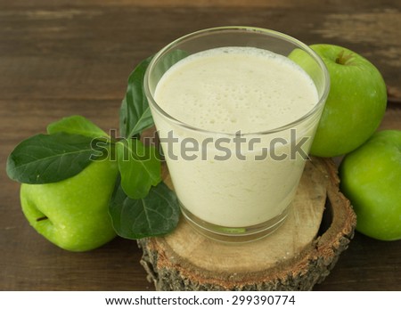 green apple smoothie in glass on wooden background