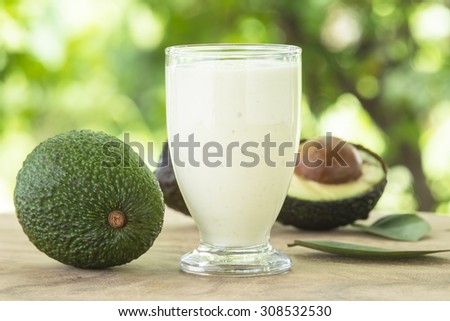 Smoothie avocado and avocado on a wooden table with background bokeh and natural light.