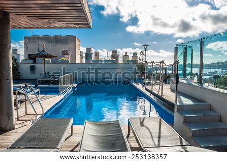 Architectural Swimming Pool at Building Rooftop in Palma de Majorca\
Tranquil Modern Architectural Swimming Pool with Lounge Chairs on the Side at the Building Rooftop Under a Cloudy Sky.