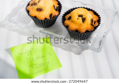 Aerial View Happy Mother\'s Day with cupcakes and text message  Appreciation green sticky note greeting card with butter pastry cakes with raisins on vintage glass plate, white natural light background