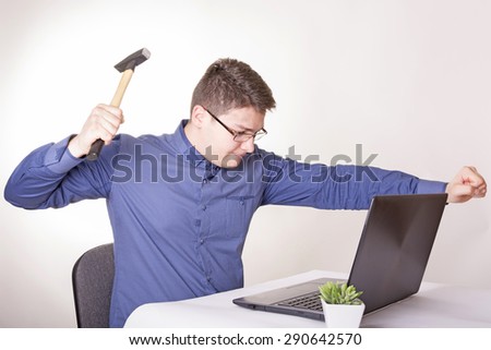 Angry businessman sitting at a desk in front of laptop