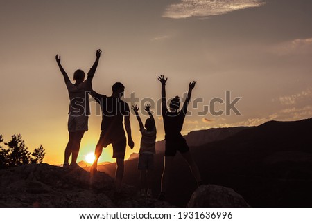 Joyful family of two parents, daughter and young son, raising arms up together. Concept of success, happiness joy of loving people.
