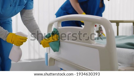 Team of professional janitors using equipment disinfecting hospital ward. Nurses in uniform cleaning furniture in empty clinic room. Healthcare and hygiene concept