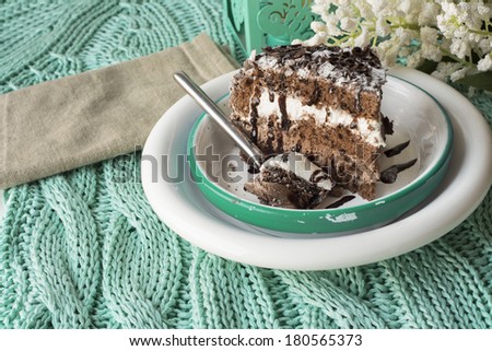 Chocolate cake on green tissue. mousse filled with chocolate and whipped cream on square plate and white flowers