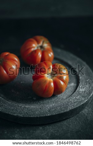 Fresh red Marmande RAF red tomatoes on black concrete dish. Grunge dark background Zdjęcia stock © 