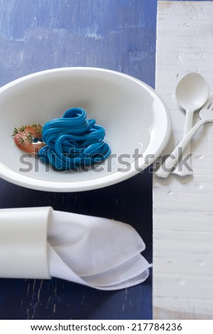 Blue Spaghetti , black place setting, pasta dyed with food coloring on rustic wooden table