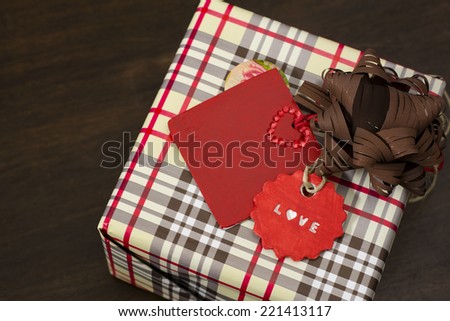 presents wrapped in checkered paper and dotted ribbon with red  label on wooden background