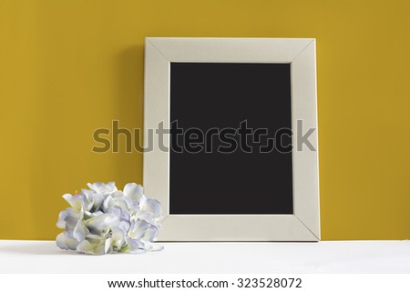empty picture frame on yellow background, decorated with blue flower