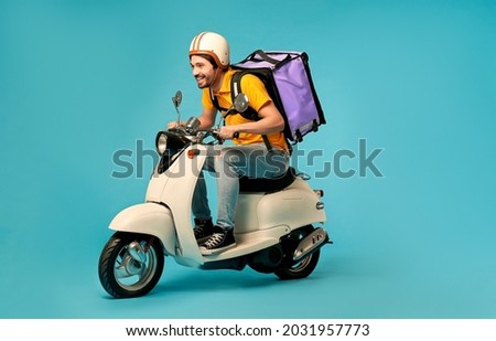 Young courier, delivery man in uniform with thermo backpack on a moped isolated on blue background. Fast transport express home delivery. Online order. Foto stock © 